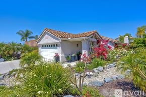 Oceanside apartment for rent - A white house with a red tile roof surrounded by green plants and trees.
