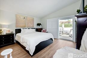 Oceanside apartment for rent - A bedroom with a large bed, a nightstand with a lamp, and a painting on the wall.