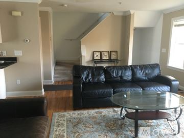 Stamford apartment for rent - A black leather couch sits in a living room with a glass table in front of it.