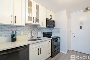 Honolulu apartment for rent - A kitchen with white cabinets and black appliances.