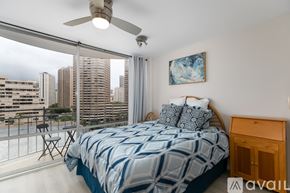 Honolulu apartment for rent - A bedroom with a large bed and a balcony overlooking a cityscape.