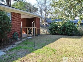 Charleston house for rent - A backyard with a brick building and a green hose.