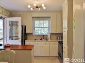 Charleston house for rent - A kitchen with white cabinets and a wooden island.