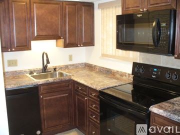 Columbus house for rent - A kitchen with brown cabinets and a black stove top oven.