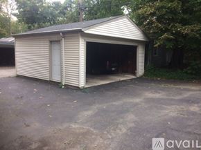 Cleveland Heights apartment for rent - A garage with a metal roof and a white door is surrounded by trees.