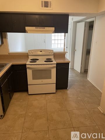 Harvey house for rent - A kitchen with a white stove top oven and black cabinets.