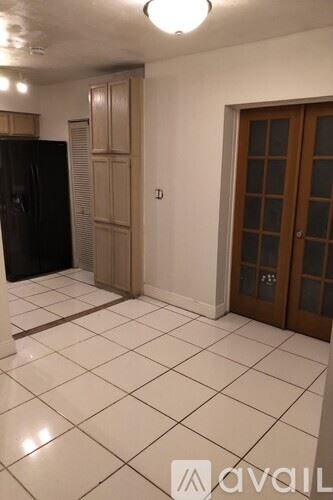 Miramar house for rent - A kitchen with a black fridge, wooden cabinetry, and a tiled floor.