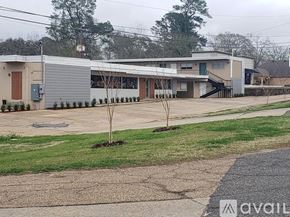 Natchitoches apartment for rent - A grey building with a tree in front of it.