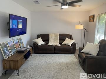 Austin house for rent - A living room with a brown couch and a flat screen TV mounted on the wall.
