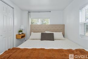 Kansas City apartment for rent - A bedroom with a bed, a nightstand with a lamp, and a window with blinds.