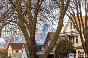Kansas City apartment for rent - A view of a residential area with houses and trees in the foreground and a city skyline in the background.