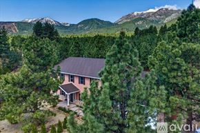 Reno house for rent - A house with a stone wall and trees in front.
