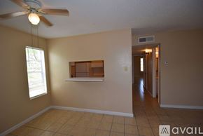 Corpus Christi apartment for rent - A room with a ceiling fan and a window with a view of trees.