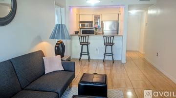 Miami condo for rent - A living room with a grey sofa and a black ottoman.