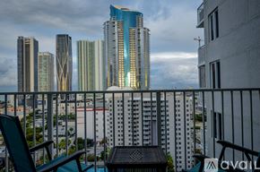 Miami condo for rent - A balcony with chairs and a table overlooks a cityscape with tall buildings.