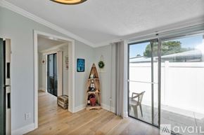 New Smyrna Beach condo for rent - A room with a wooden floor and a white wall with a hanging decoration.