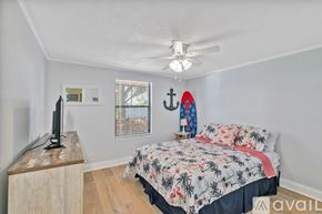 New Smyrna Beach condo for rent - A bedroom with a bed, a television, and a window with blinds.