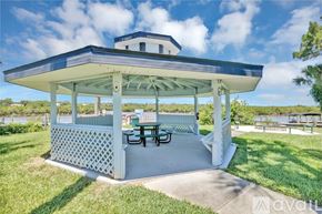 New Smyrna Beach condo for rent - A pavilion with a table and chairs is set up in a grassy area.