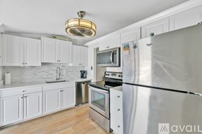New Smyrna Beach condo for rent - A kitchen with white cabinets and a stainless steel refrigerator.