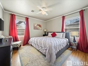 Tulsa house for rent - A bedroom with a large bed and red curtains.