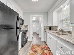Tulsa house for rent - A kitchen with black appliances and white cabinets.