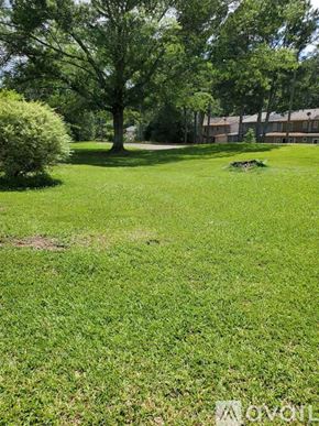 Snellville townhouse for rent - A grassy field with a tree and a building in the background.