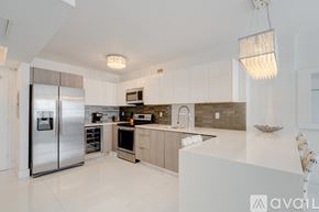 Miami Beach condo for rent - A modern kitchen with a stainless steel refrigerator and a white countertop.