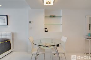 Miami Beach condo for rent - A modern dining room with a glass table and white chairs.