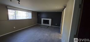 Cheney house for rent - A large empty room with a fireplace and a window.
