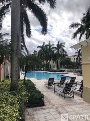Palm Beach Gardens condo for rent - A pool surrounded by palm trees and lounge chairs.
