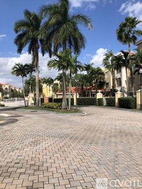Palm Beach Gardens condo for rent - A paved courtyard with palm trees and a white fence.