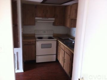 Gretna house for rent - A kitchen with a white stove top oven and wooden cabinets.