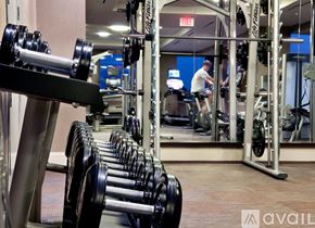 Jersey City apartment for rent - A gym with a row of dumbbells in the foreground and a man working out in the background.