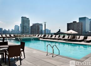 Jersey City apartment for rent - A pool area with chairs and a city skyline in the background.