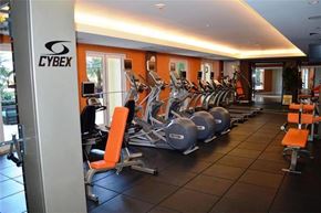 West Palm Beach apartment for rent - A gym with orange walls and a sign that says "CYBEX".