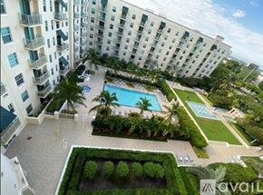 West Palm Beach condo for rent - A large white building with a pool and greenery.