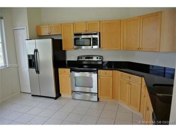 Palm Beach Gardens condo for rent - A kitchen with wooden cabinets and black countertops.