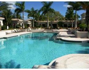 Palm Beach Gardens condo for rent - A swimming pool surrounded by palm trees and lounge chairs.