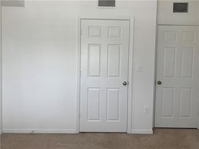 West Palm Beach condo for rent - A white door is in a room with a carpet floor.