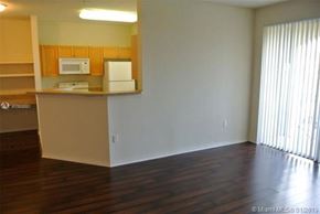 Palm Beach Gardens condo for rent - A kitchen with white appliances and wooden cabinets.