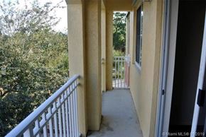 Palm Beach Gardens condo for rent - A balcony with a white railing and a view of trees.