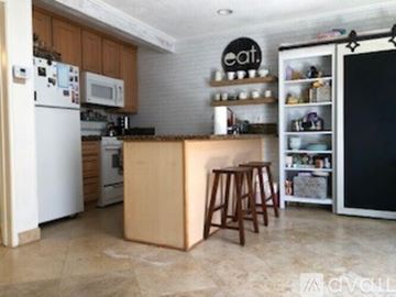 Newport Beach apartment for rent - A kitchen with a white refrigerator, wooden island, and a black fridge freezer.