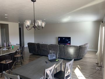 Bluffdale house for rent - A modern living room with a grey couch and a wooden dining table.