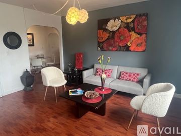 Miami apartment for rent - A living room with a grey couch, a white chair, a coffee table, and a painting on the wall.
