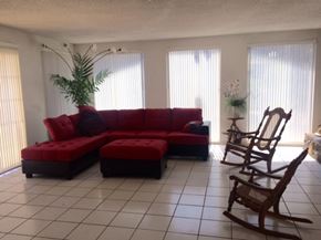 Palmdale apartment for rent - A red couch with a bench in front of it and a rocking chair to the side.