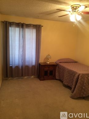 Palmdale apartment for rent - A bedroom with a bed, nightstand, and window with curtains.