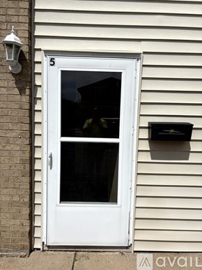 Pekin house for rent - A white door with a glass window and a mailbox on the siding of a house.