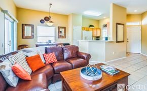 Marana house for rent - A bedroom with a large bed, a ceiling fan, and a window overlooking a garden.