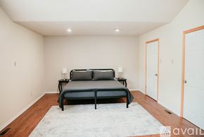 Sherwood house for rent - A bedroom with a black bed and a white rug.