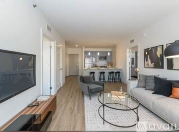 Chicago house for rent - A modern living room with a grey sofa, a glass coffee table, and a television on the left side.